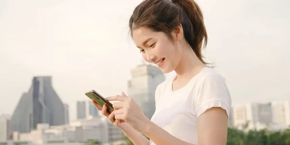 a happy young woman uses her mobile phone in Thailand